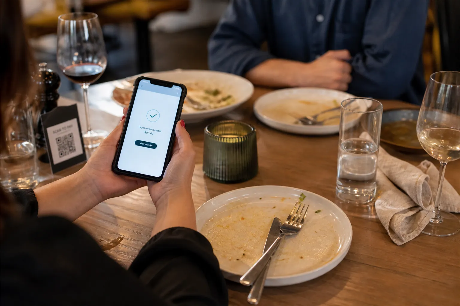 Guest paying the check on their phone at the table after a meal